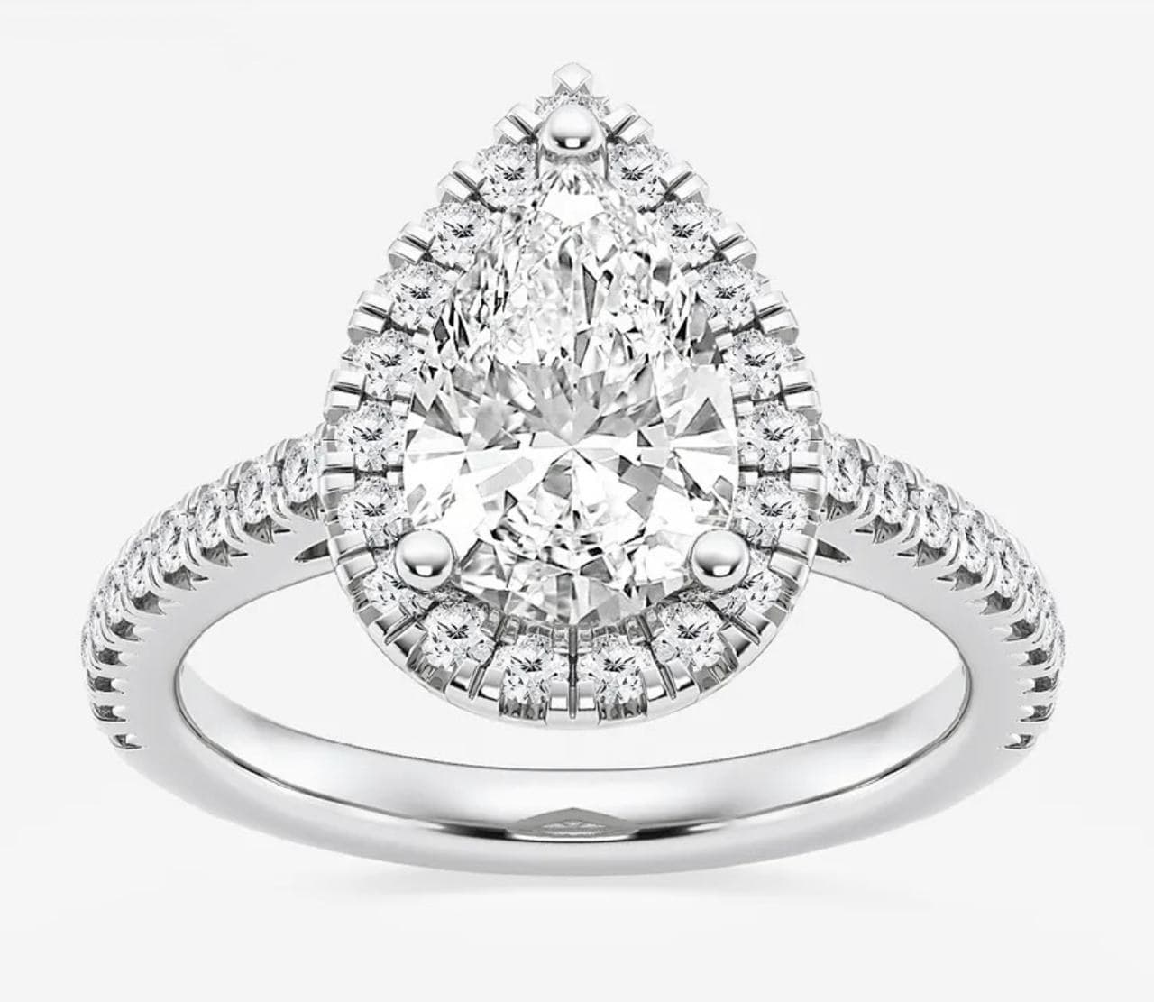 A pear-shaped diamond halo ring with a pavé band in white gold